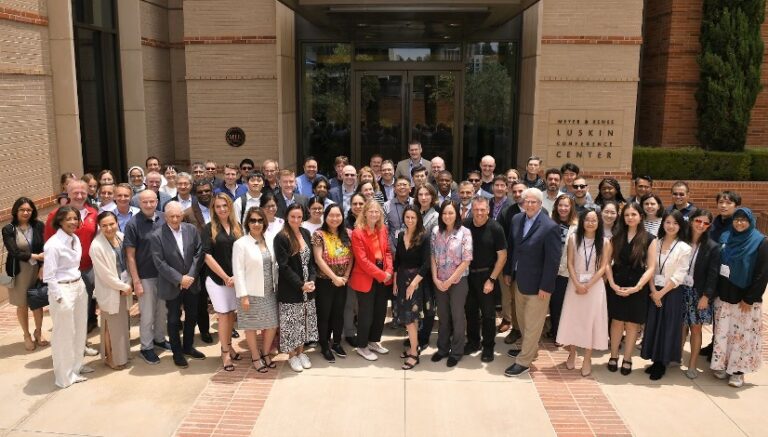 Group of scientists smile for the camera in front of a building