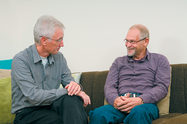 two caucasian men talking on couch