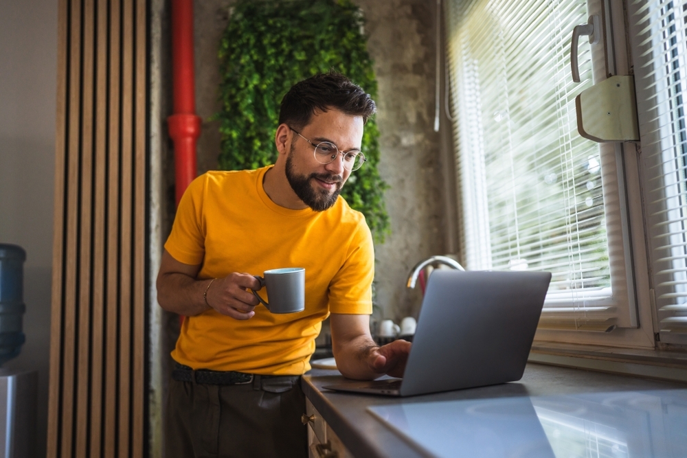adult man holding coffee mug while on his computer